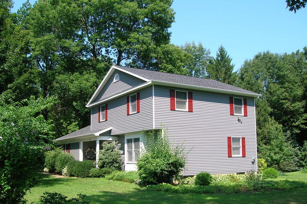 Two-story home refinished with red accent shutters