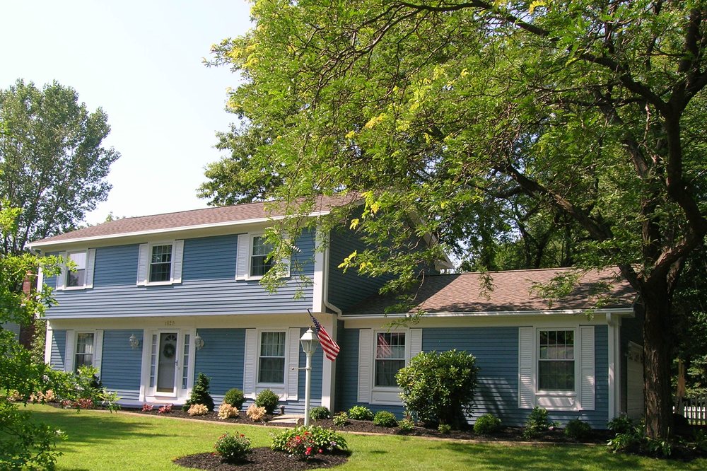 Blue two-story colonial home refinished with white trim and flag