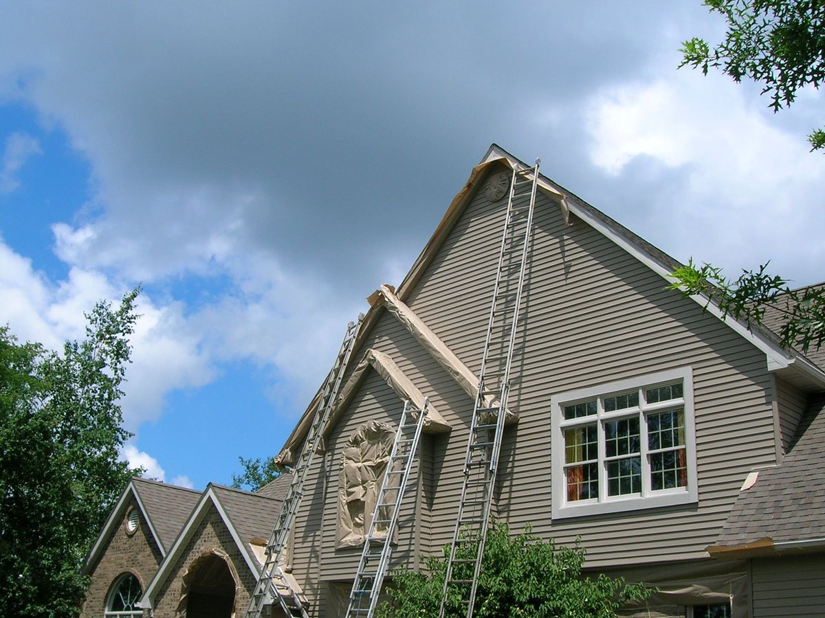 The Aluminum Refinishing crew at work on an Erie home — ladders set, windows masked, ready to refinish