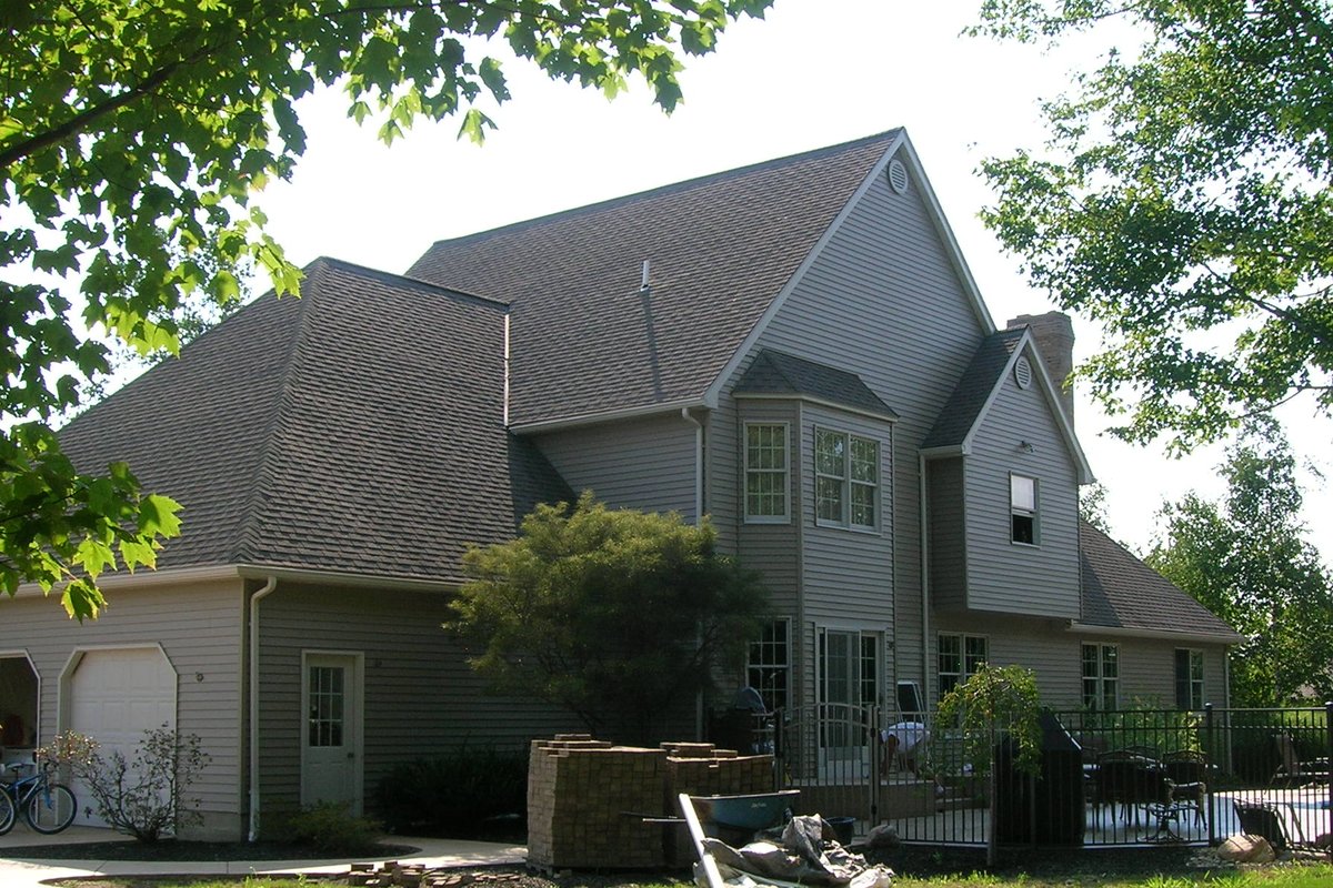 Large Erie home after refinishing — fresh sage-green finish, pool fence and stone patio visible